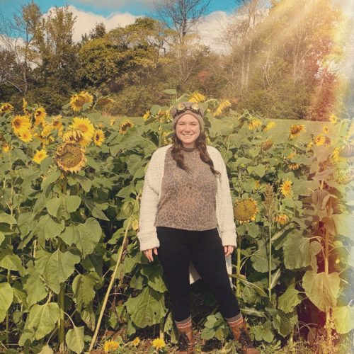 employee standing with sunflowers