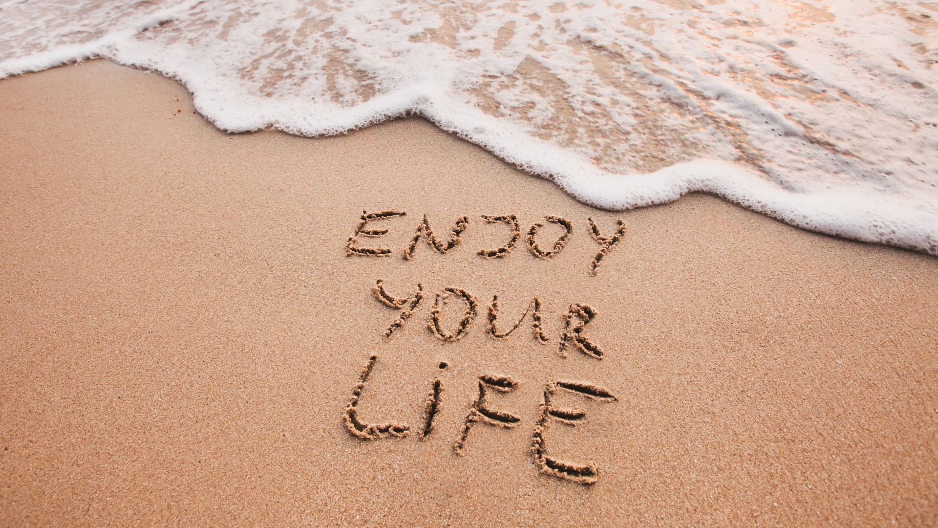 words written in sand on a beach with the water almost touching them